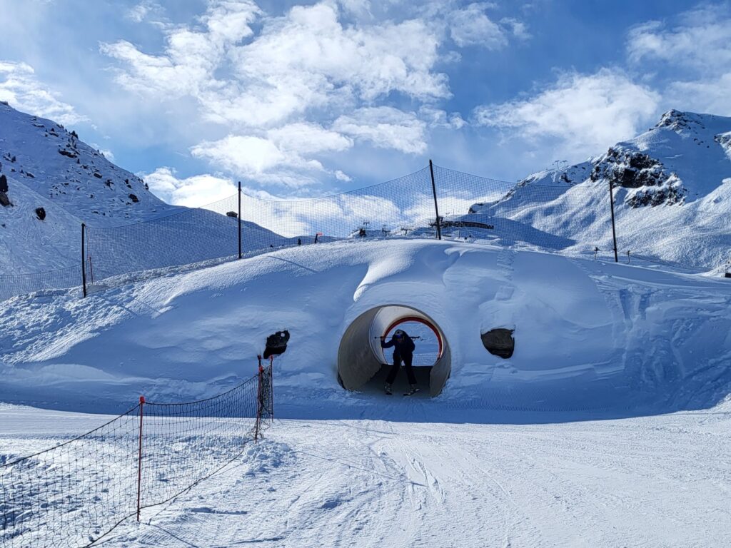 Beginner skier passing through snow tunnel on a green piste in Méribel-Mottaret.